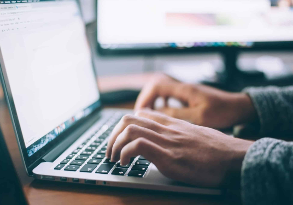 Une personne concentrée en train de taper sur son clavier, illustrant la productivité au bureau.
