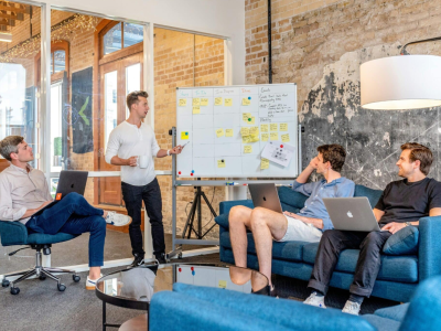 Réunion d'équipe dans une salle de conférence, avec quatre collaborateurs engagés dans une discussion professionnelle.